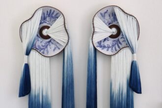 a wall installation made using blue-and-white fiber and blue-and-white glazed ceramic plates with the fiber connecting through holes in the plates and draping elegantly