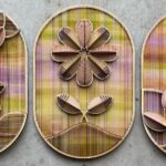 a trio of vibrant embroidered sculptural flowers on wood oval panels