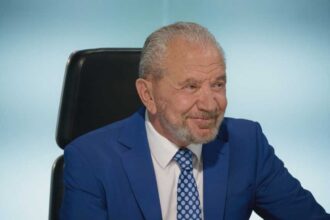 Lord Sugar smiling in the boardroom