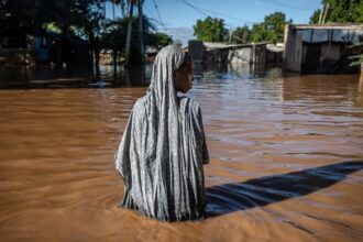 A woman wades through flood waters that inundated a residential area in Garissa, Kenya, following torrential rains in May, 2024.