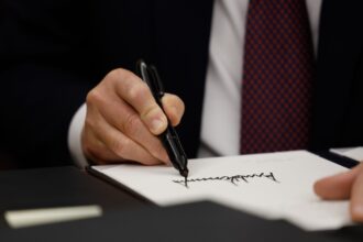 Close-up of hand holding a sharpie and signing a piece of paper