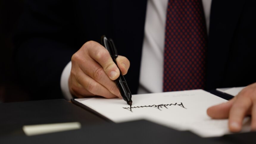 Close-up of hand holding a sharpie and signing a piece of paper