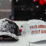 Snow covers MAGA hats for sale outside the rally.