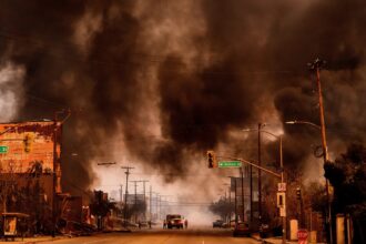 Black smoke fills the sky over a neighborhood burning in Los Angeles.